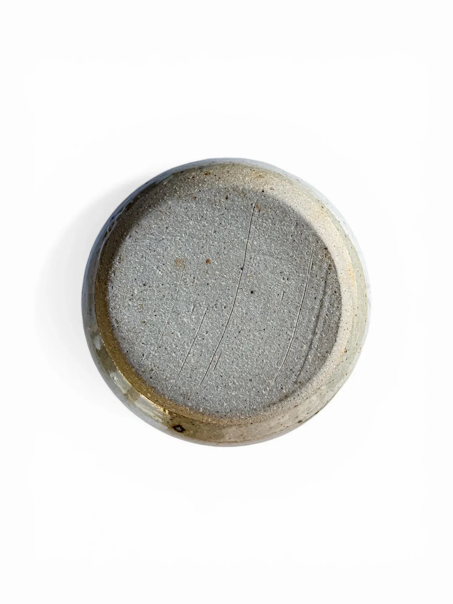 A view of the underside of the vintage lidded server. It displays the raw, unglazed, wire-cut grey stoneware clay base, featuring characteristic firing imperfections and the absence of a maker's mark, confirming its handmade studio pottery origin.