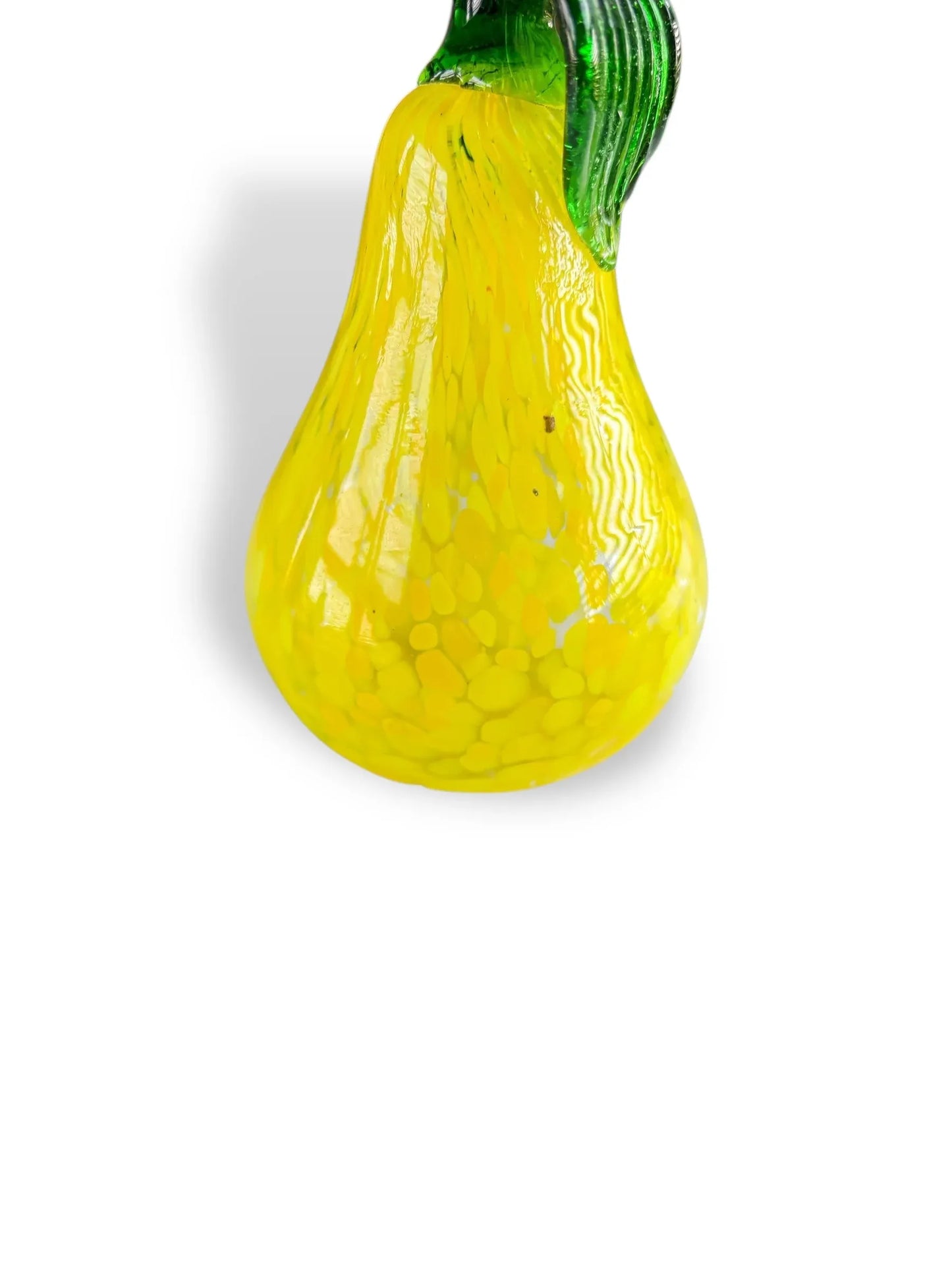 Close-up of yellow glass pear decoration with green leaf on white background