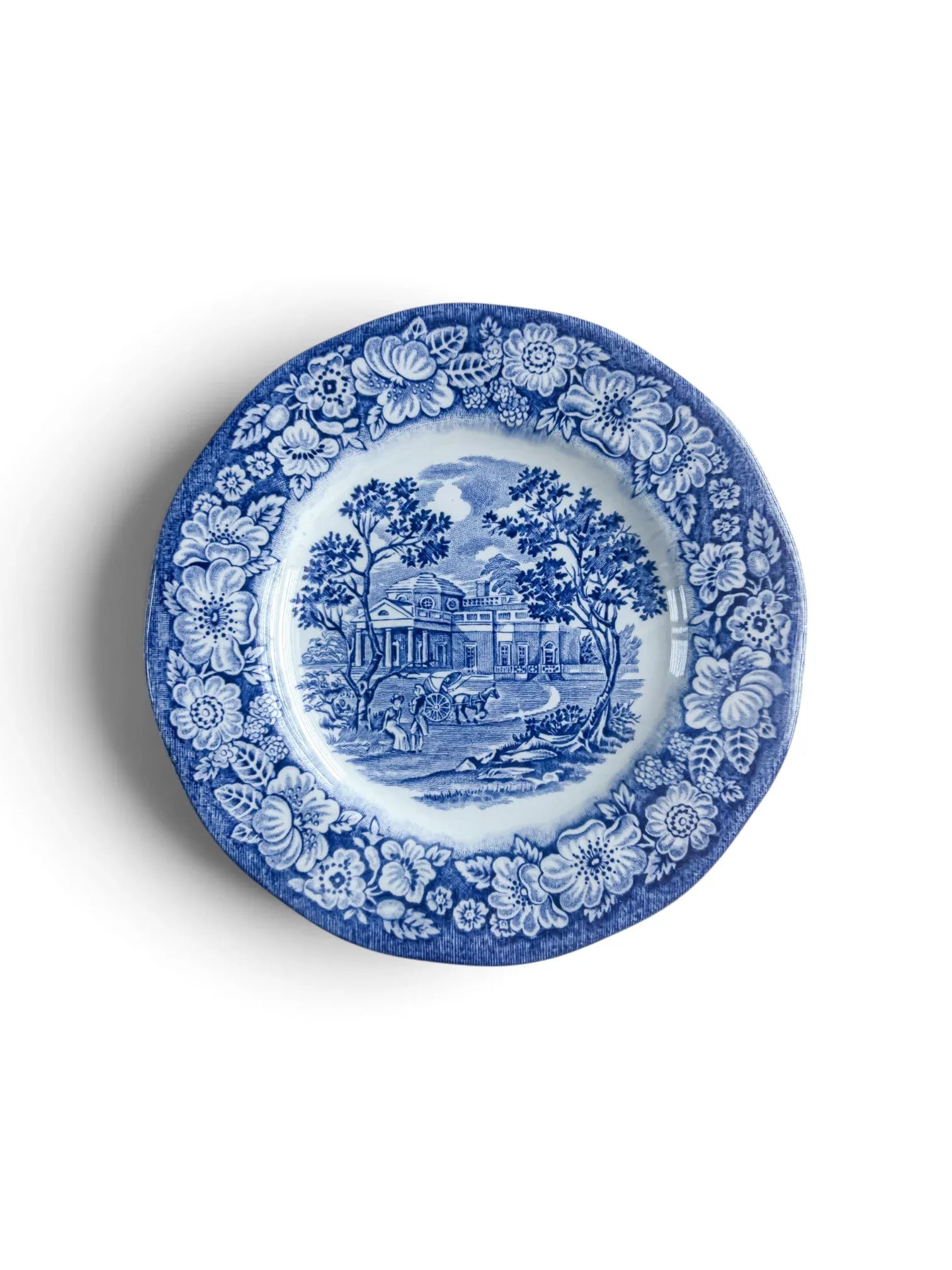 Liberty Blue Staffordshire ironstone bread and butter plate, 15.1 cm, showing the Monticello scene in cobalt transferware with a floral rose border, photographed from above on a white background.