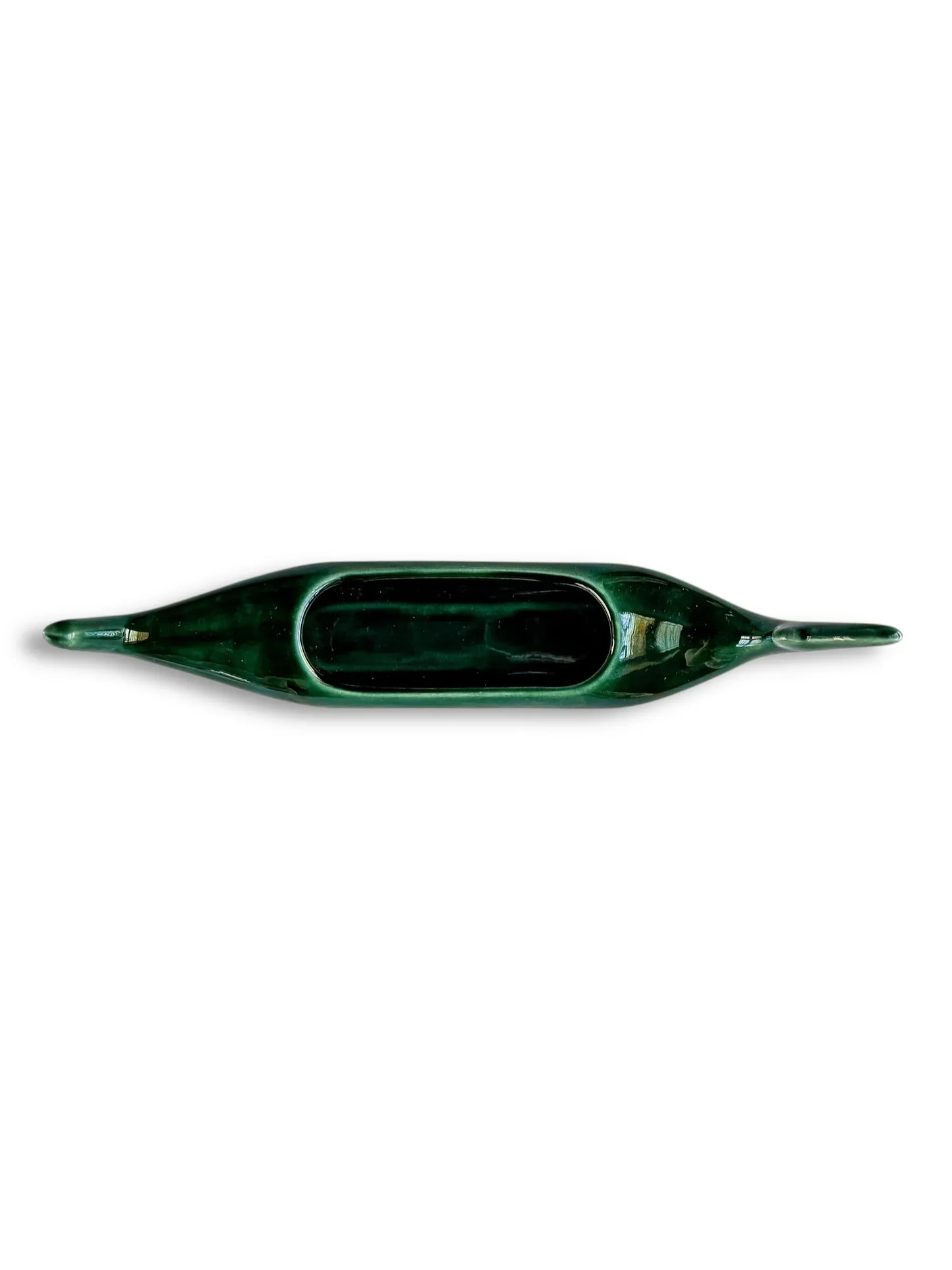 Top view of dark green ceramic canoe-shaped dish with elongated ends on white background