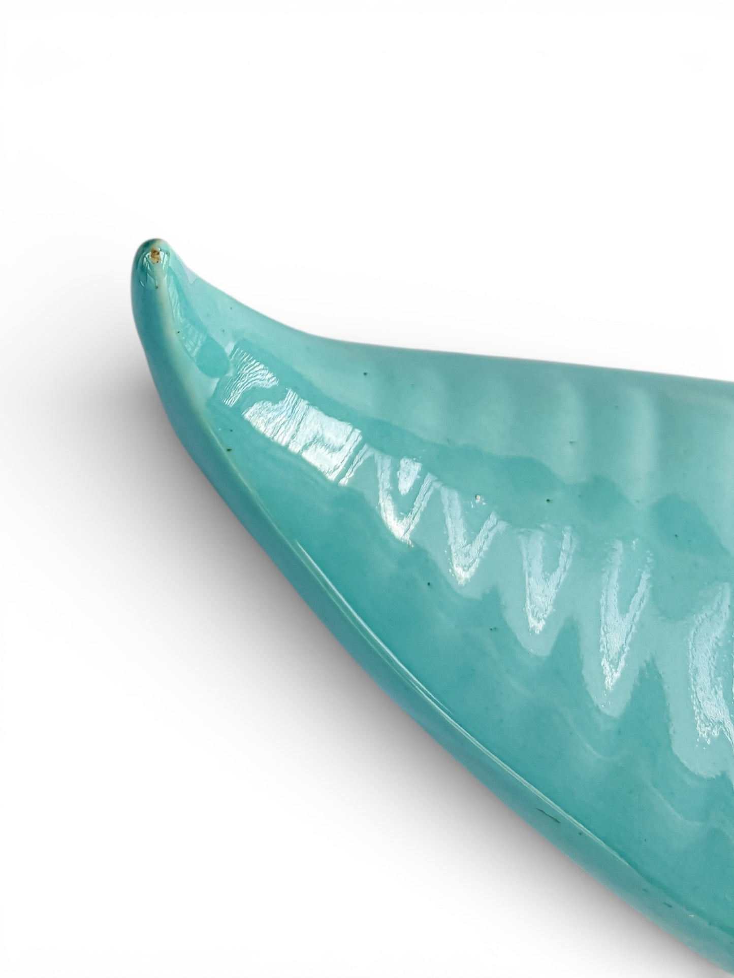 Glossy turquoise ceramic dish with curved edge on white background