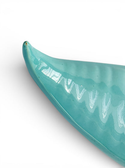 Glossy turquoise ceramic dish with curved edge on white background