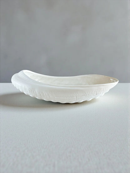 White ceramic shell-shaped decorative bowl with textured design on white surface