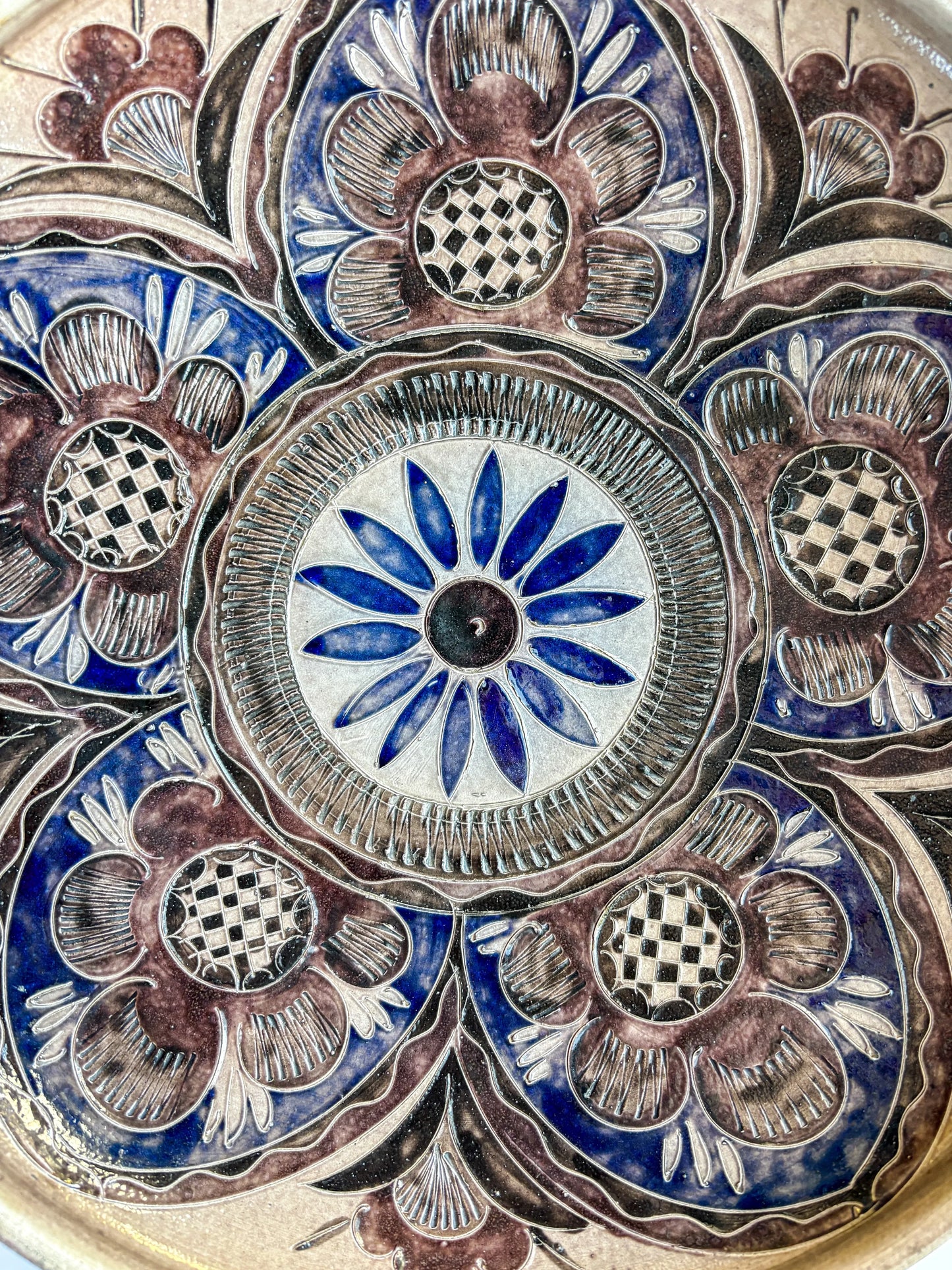 Close-up of hand-carved sgraffito floral pattern showing salt-glaze orange peel texture.