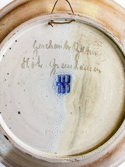 Handwritten cursive Geschwister Bahn Höhr-Grenzhausen signature on reverse of ceramic charger along with the Embossed HK workshop mark and Holbeck and Kracht gallery stamp on vintage pottery base.