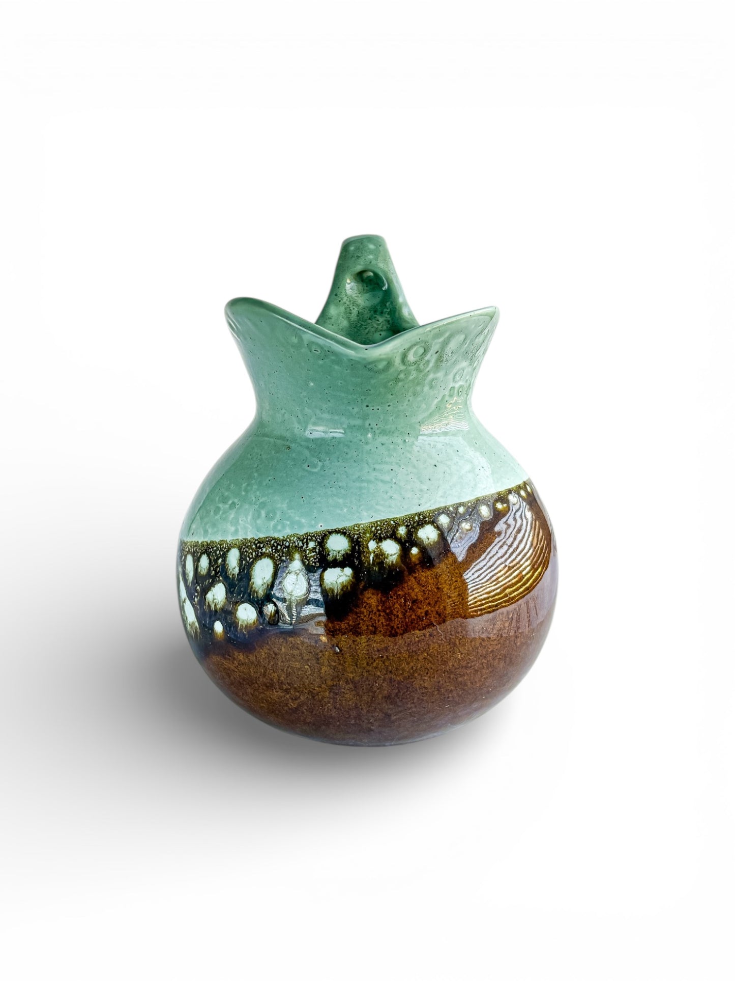 Handcrafted ceramic pitcher with a green top half and brown bottom half, featuring unique textured glaze