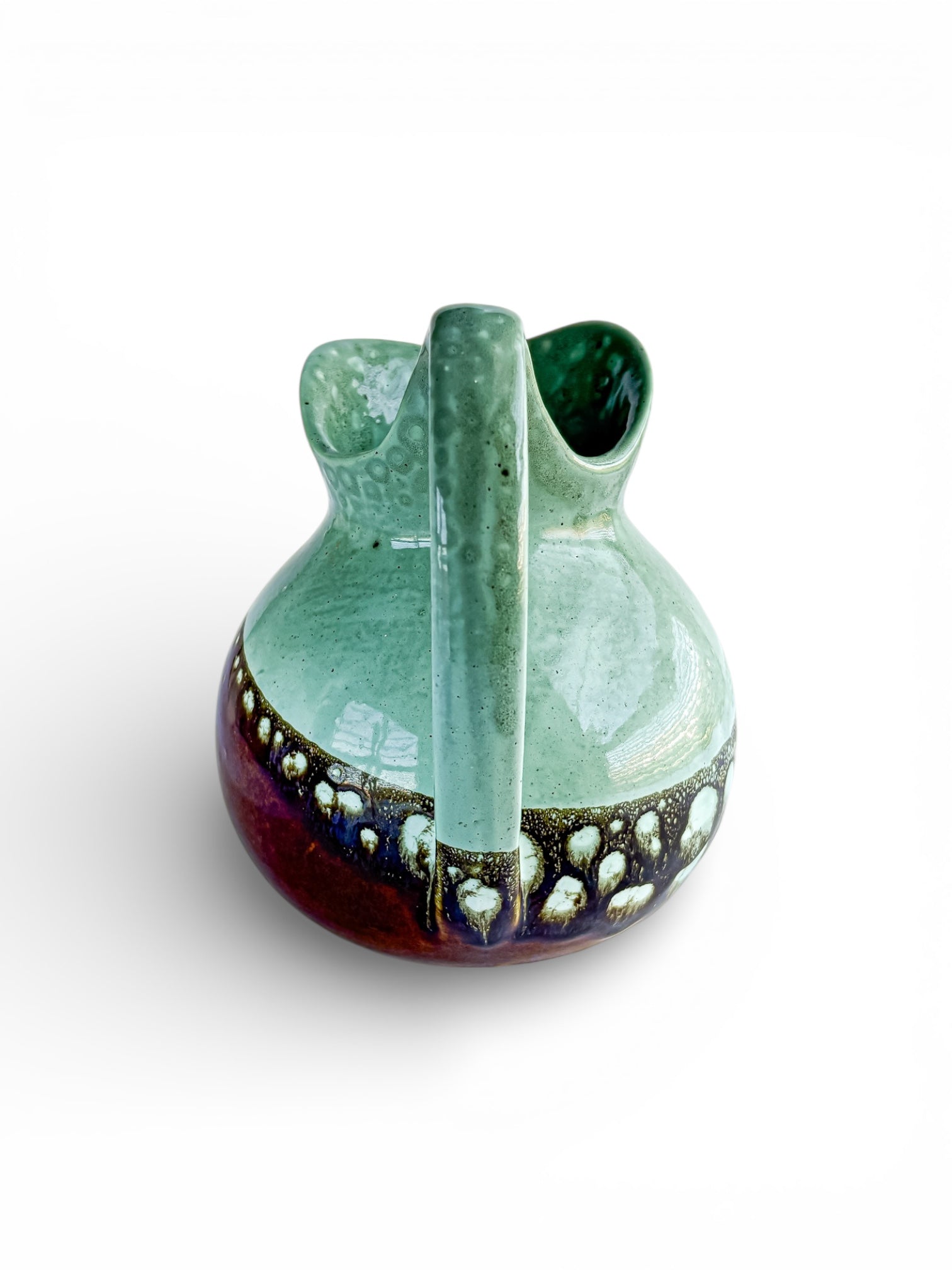 Curved ceramic pitcher with green top and patterned blue-brown base, glazed vintage handmade pottery