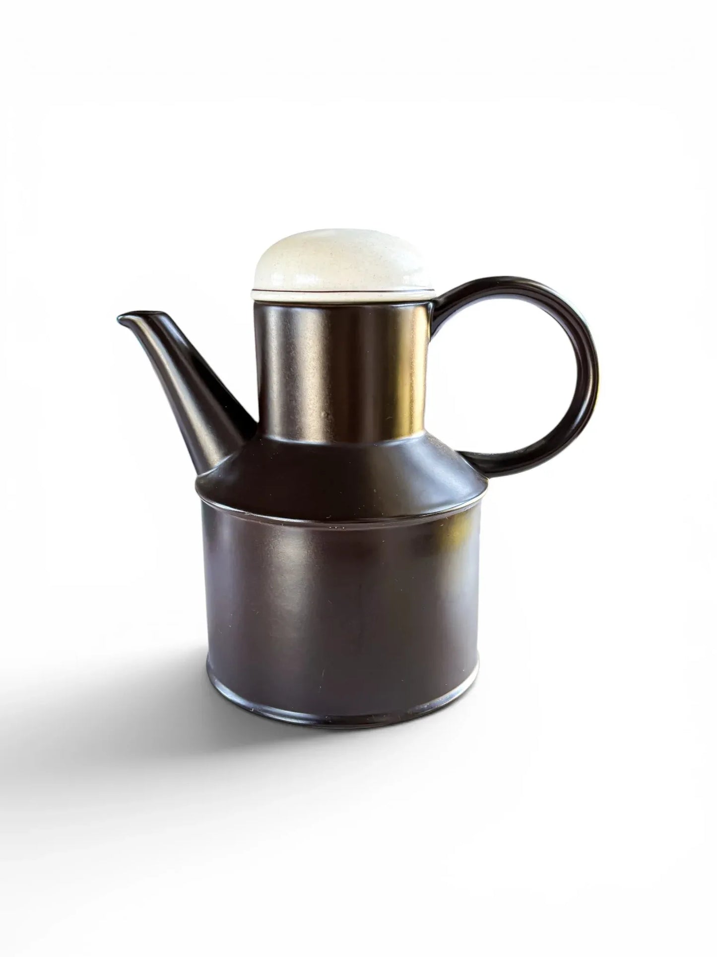 Side profile of a vintage Midwinter Stonehenge coffee pot in Onyx. The tall, cylindrical ceramic body is a deep chocolate brown with a matte finish, topped with a speckled oatmeal-colored lid against a clean white background.