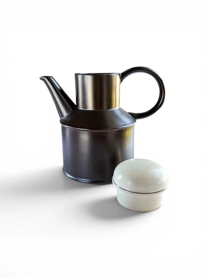 A 1970s Midwinter Stonehenge coffee pot shown with its lid placed beside it. The rich, dark earth-brown stoneware body features a bold circular handle and a high-set spout, highlighting the contrasting speckled "Creation" glaze on the lid.