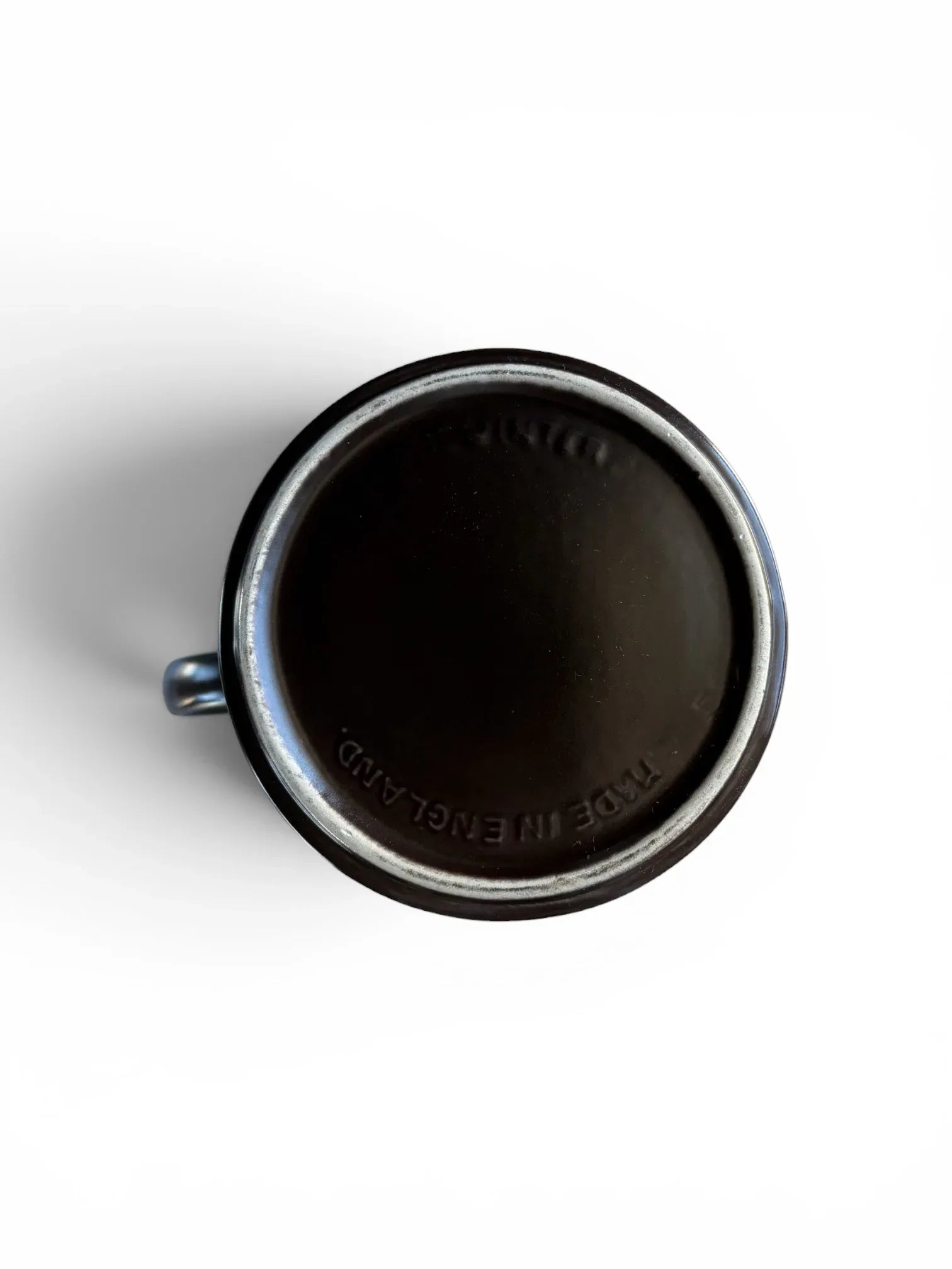 The underside of a Midwinter Stonehenge coffee pot showing the embossed "Midwinter Made in England" maker's mark on the dark brown stoneware base. The unglazed foot ring shows authentic vintage wear.