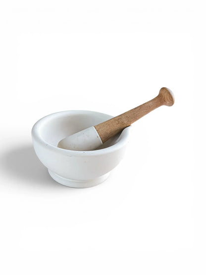 Side profile view of a vintage white porcelain Milton Brook mortar and pestle, highlighting the smooth glazed exterior and the ergonomic turned beechwood handle.