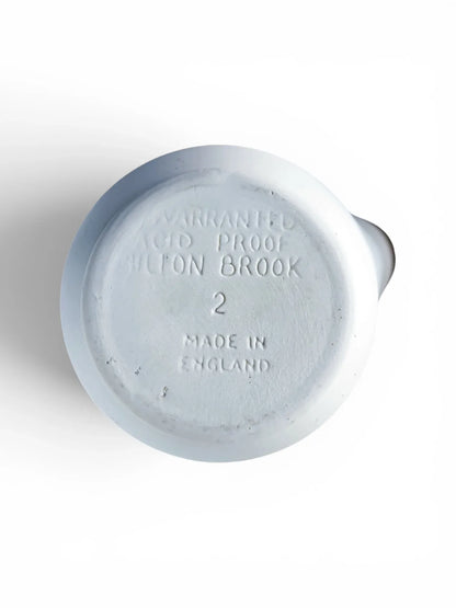Close-up of the underside of a Milton Brook mortar bowl, showing the crisp, incised English maker's stamp reading Warranted Acid Proof, Milton Brook, 2, Made in England.