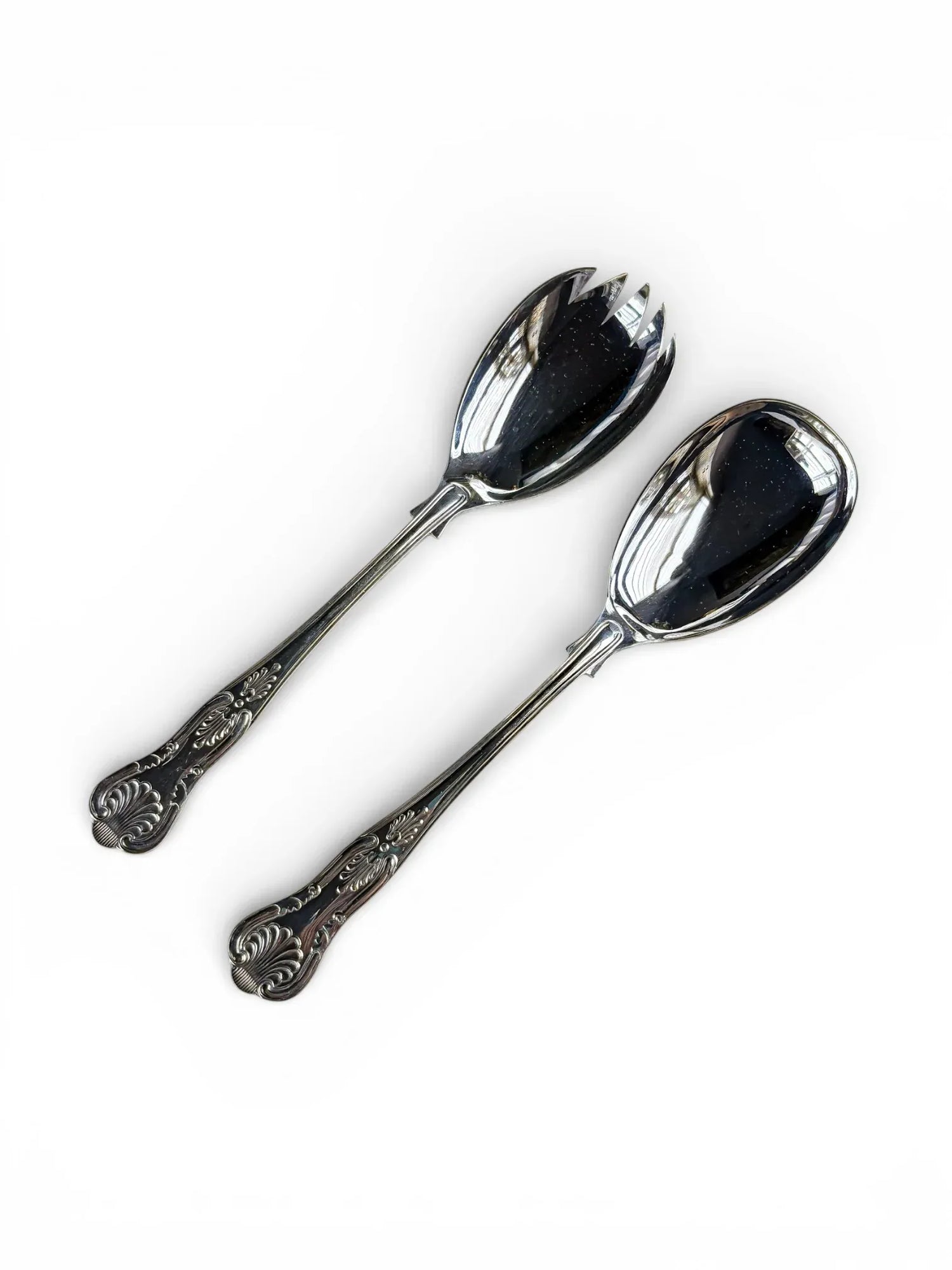 Vintage silver plated serving spoon and fork with ornate handles on white background.