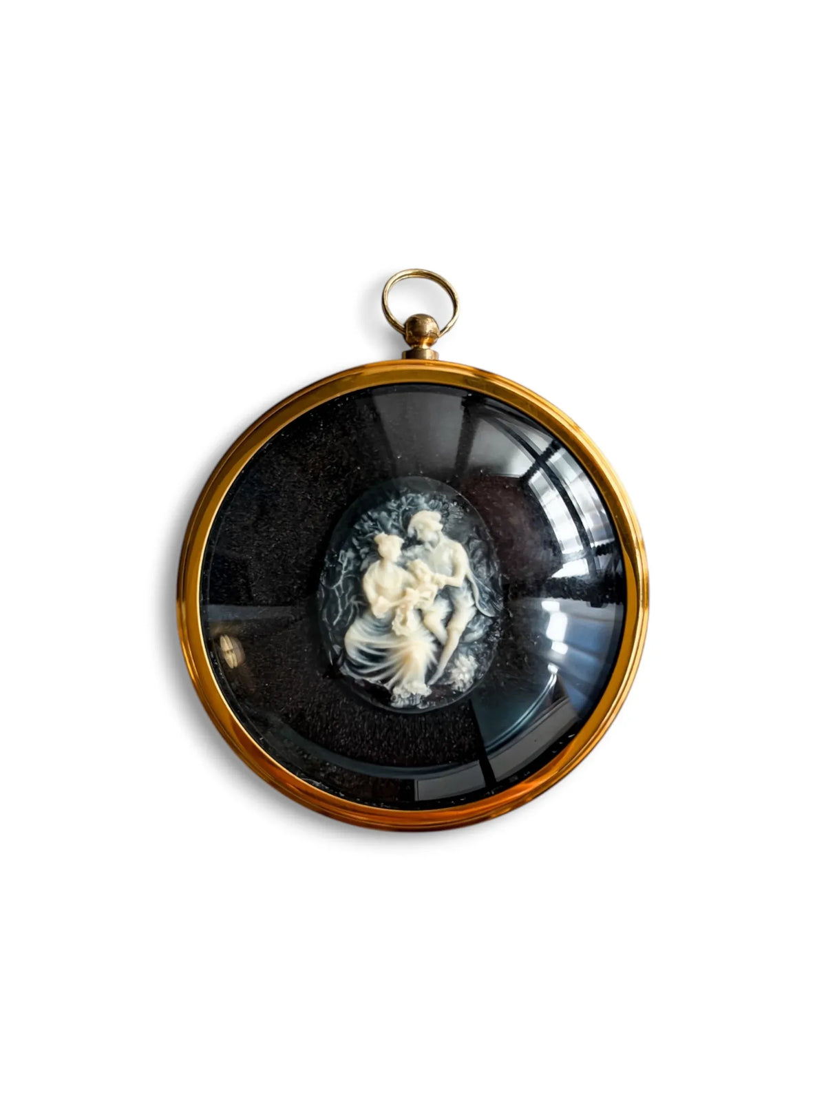 A round gilt-framed Peter Bates cameo of a boy and girl seated together, the girl holding a posy, in white relief on a black ground, with a hanging ring.
