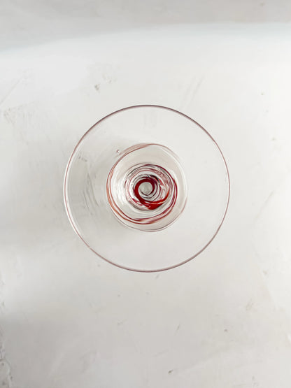 Top view of a clear glass with red wine residue swirled at the bottom on a white surface