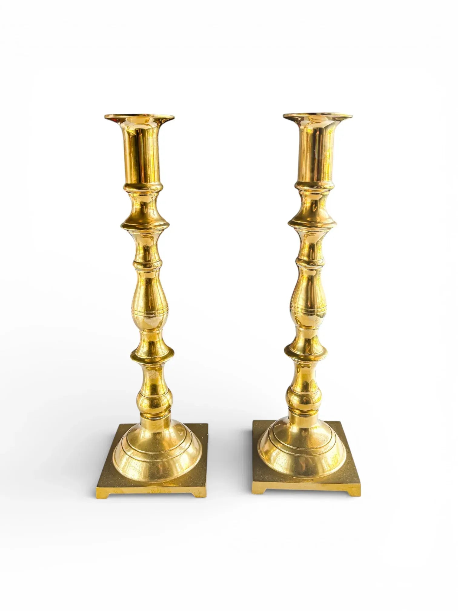 Pair of vintage brass candlesticks with ornate design on white background