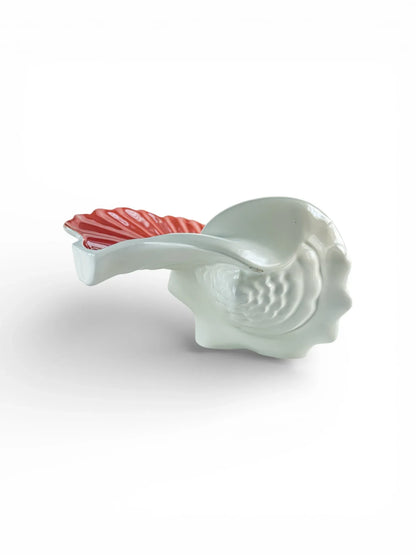 Porcelain shell-shaped serveware with white base and pink accent handle on white background