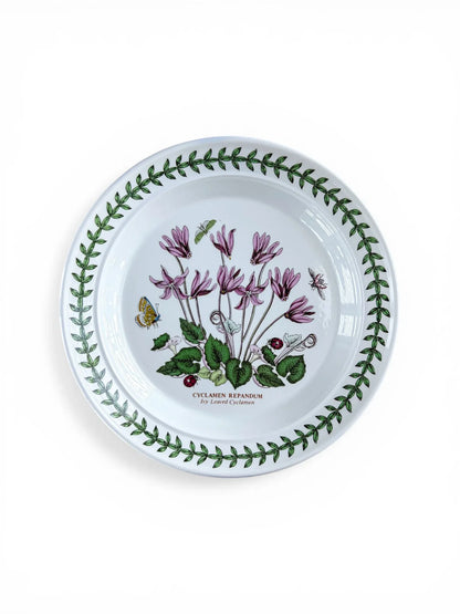 Overhead view of a Portmeirion Botanic Garden bread and butter plate featuring the Cyclamen Repandum motif, centered with magenta flowers and a green leaf trefoil border on a white background.