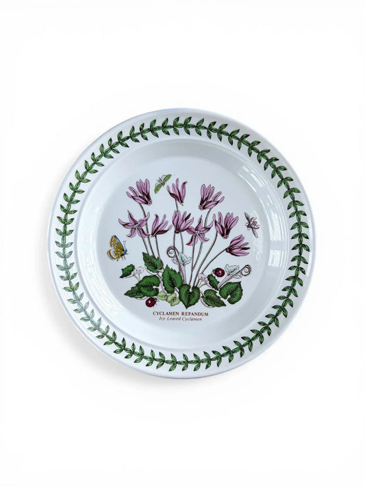 Overhead view of a Portmeirion Botanic Garden bread and butter plate featuring the Cyclamen Repandum motif, centered with magenta flowers and a green leaf trefoil border on a white background.