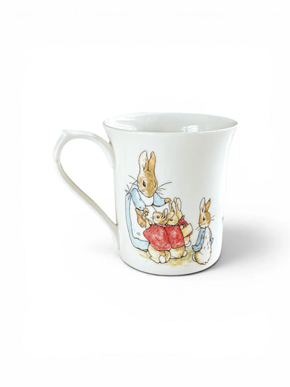 Illustration of Mrs. Rabbit with Flopsy, Mopsy, and Cotton-tail on a Queen’s centenary mug.