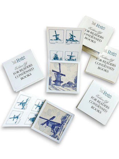 A curated collection of six vintage Regina Delft Blue windmill tiles with original Reader’s Digest Condensed Books presentation sleeves and informational inserts on a clean white background.