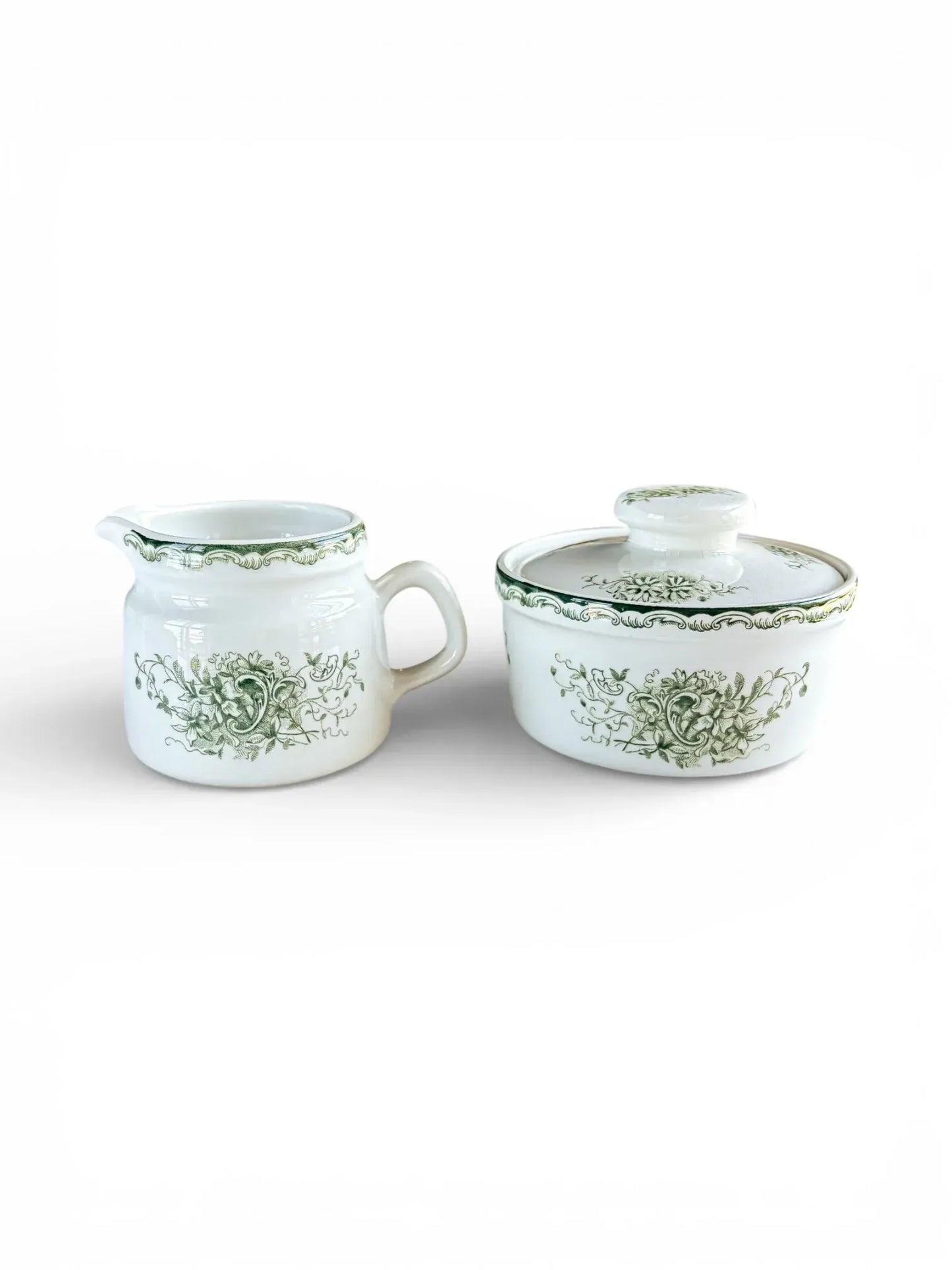 Profile shot of the Rörstrand Grön Anna creamer and lidded sugar bowl set with forest green floral patterns on white flintware.