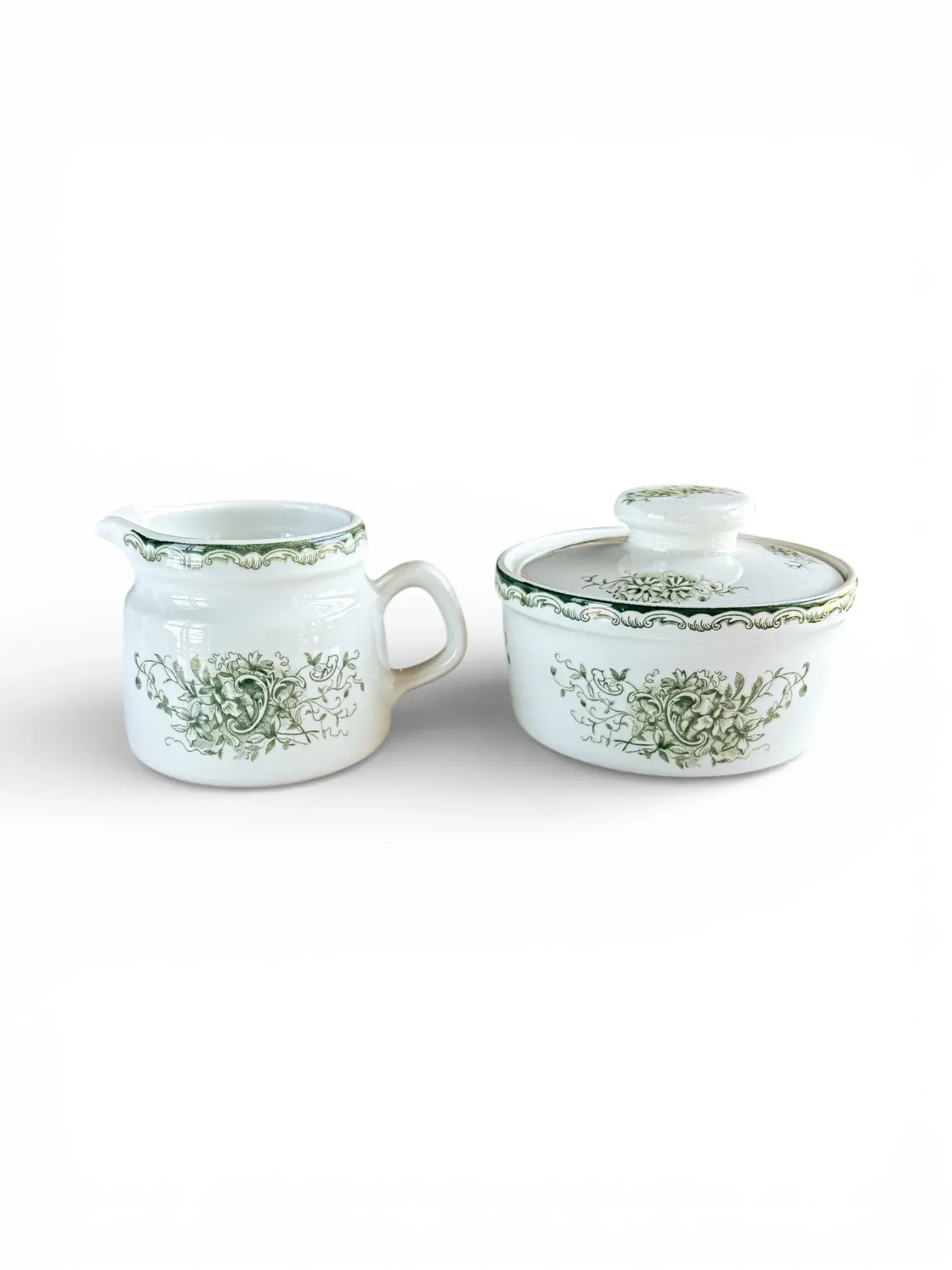 Profile shot of the Rörstrand Grön Anna creamer and lidded sugar bowl set with forest green floral patterns on white flintware.