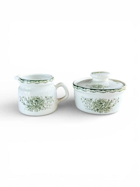Profile shot of the Rörstrand Grön Anna creamer and lidded sugar bowl set with forest green floral patterns on white flintware.