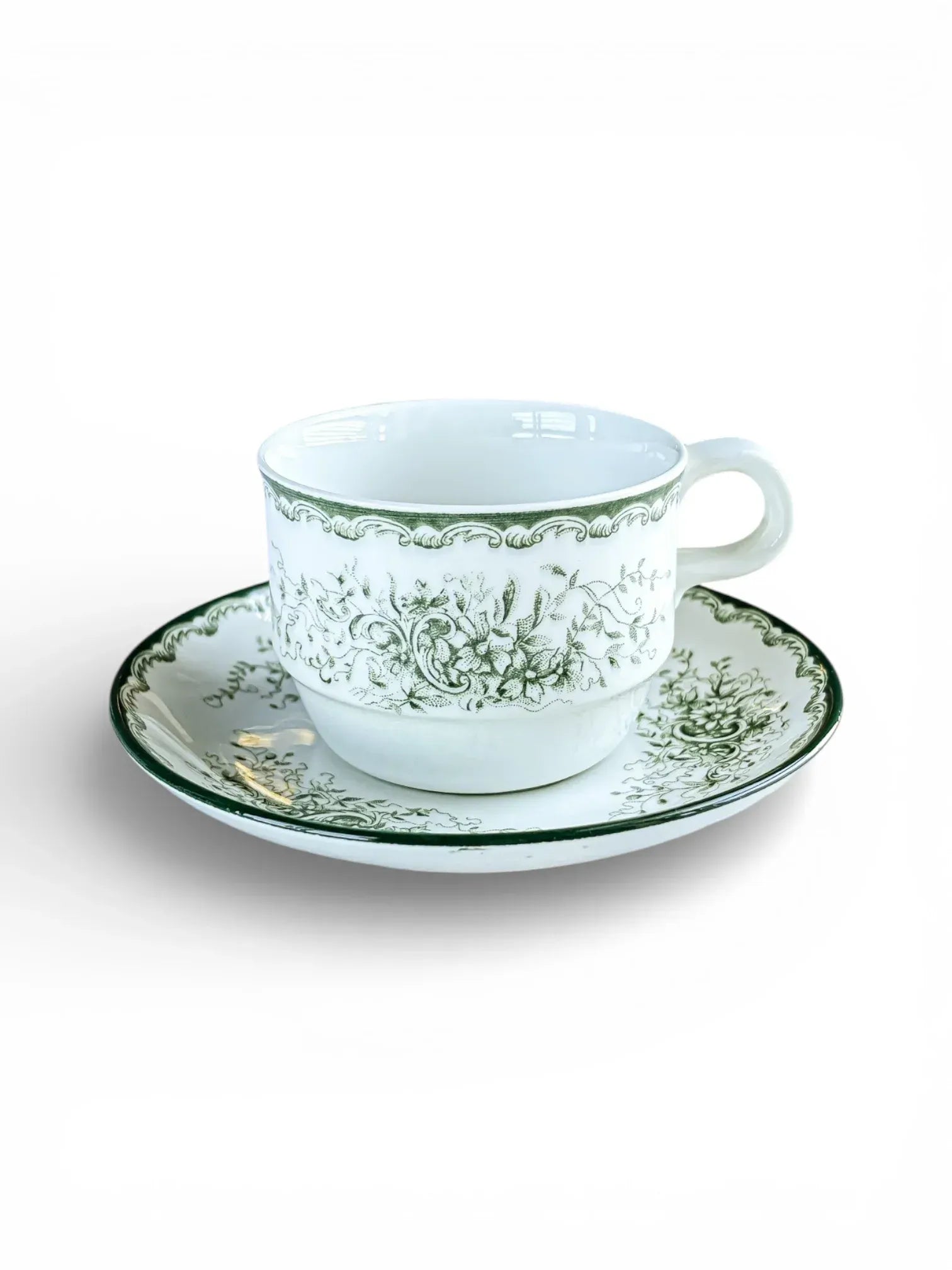 A side-view studio shot of a Rörstrand Grön Anna stackable coffee cup and matching saucer, featuring the signature green floral pattern and a recessed base for easy stacking.