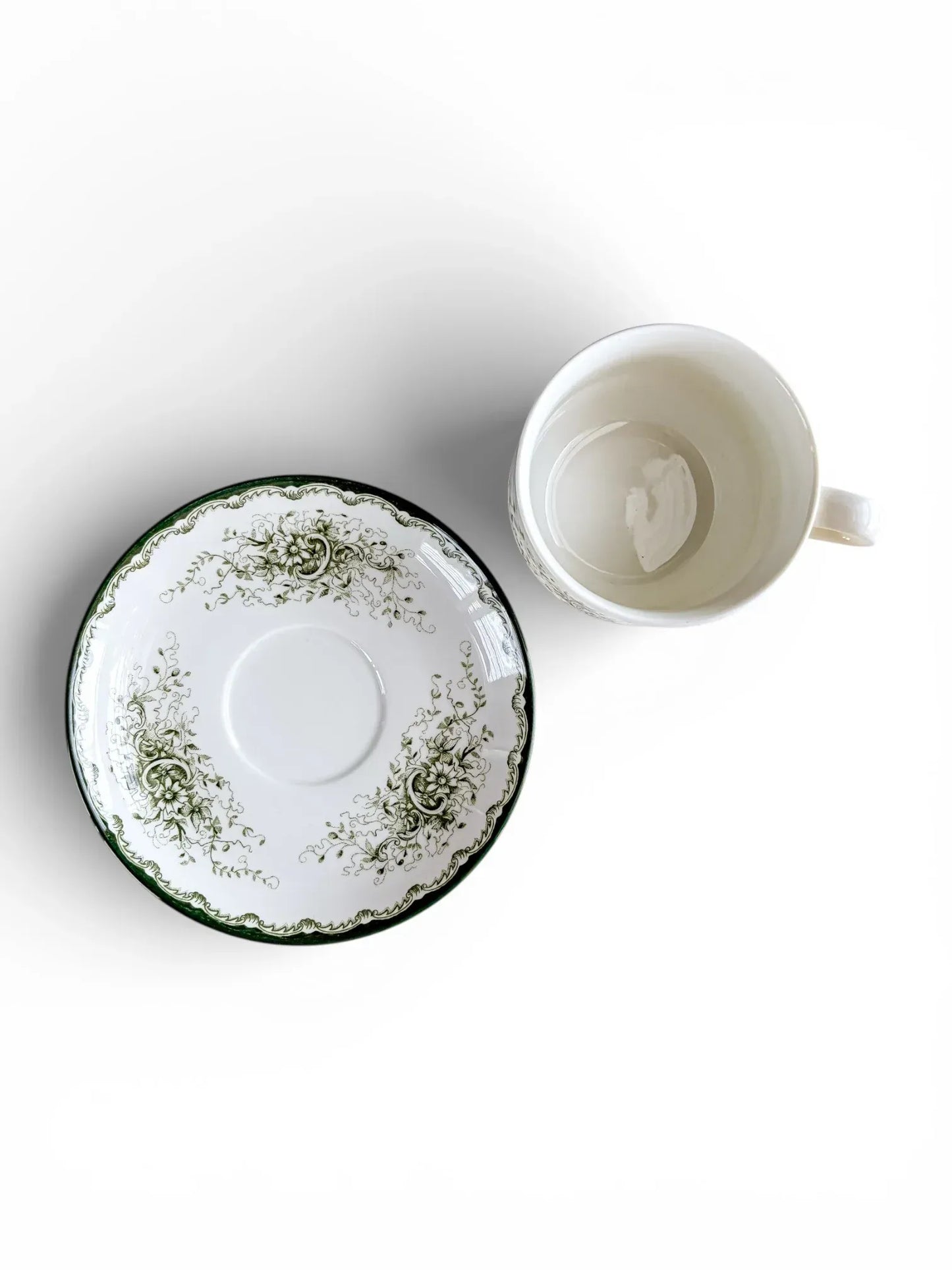 A top-down perspective showing the interior of a 200 ml Rörstrand Grön Anna cup alongside its saucer, highlighting the crisp white glaze and forest green decorative border.