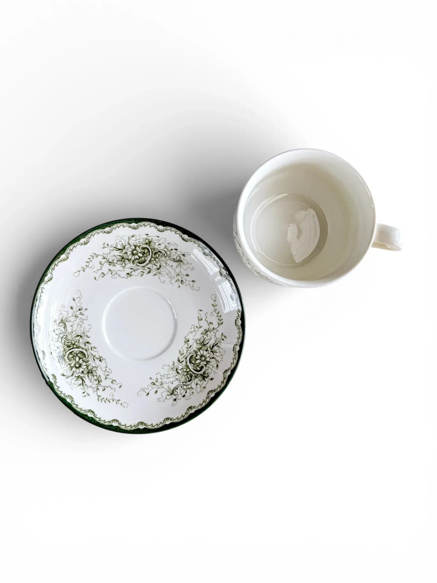 A top-down perspective showing the interior of a 200 ml Rörstrand Grön Anna cup alongside its saucer, highlighting the crisp white glaze and forest green decorative border.