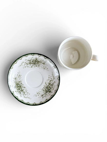 A top-down perspective showing the interior of a 200 ml Rörstrand Grön Anna cup alongside its saucer, highlighting the crisp white glaze and forest green decorative border.