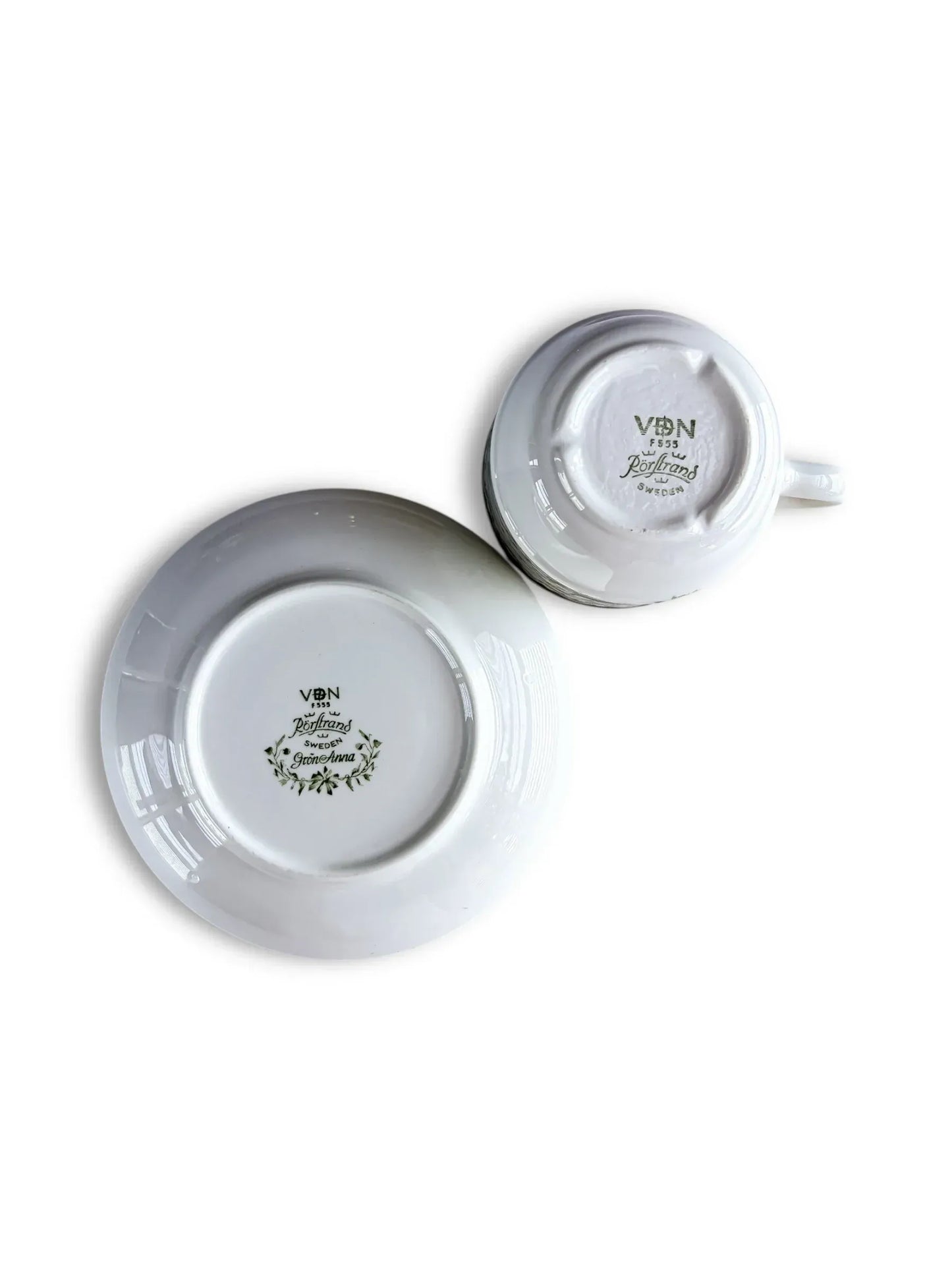 The undersides of the Grön Anna cup and saucer, clearly showing the green "Rörstrand Sweden" backstamps and the VDN F555 quality certification code.