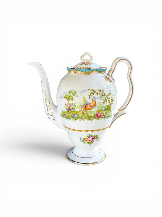 Full profile view of a vintage Royal Albert Chelsea Bird fine bone china coffee pot in the Gainsborough shape against a clean white background. The piece features a vibrant, exotic bird vignette, a flared pedestal foot, an elegant gilded S-scroll handle, and a sweeping spout.