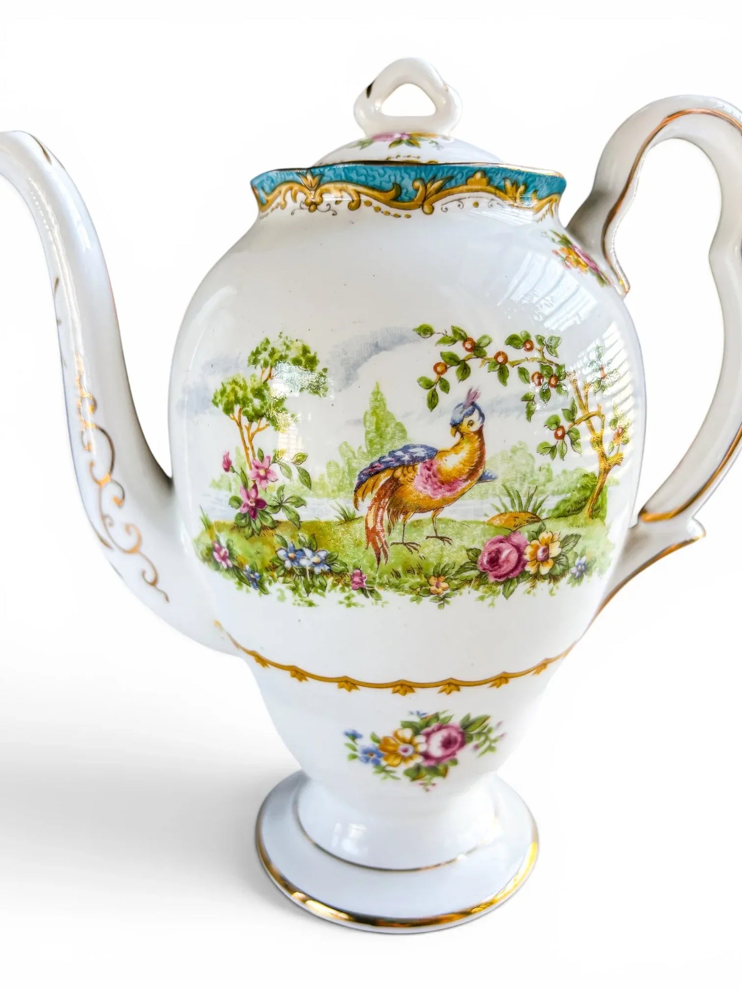 A detailed close-up of the central Chelsea Bird transfer-print design on the porcelain body, showcasing the brightly coloured fantasy bird surrounded by detailed pink, blue, and yellow garden flowers under a leafy tree branch.