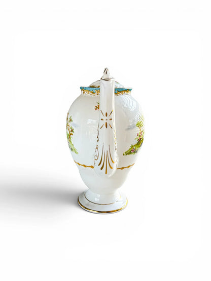 Front-facing view of the coffee pot focusing on the elongated, fluted spout. The shot highlights the intricate, vertical gold scrollwork and accents running down the length of the white porcelain spout.