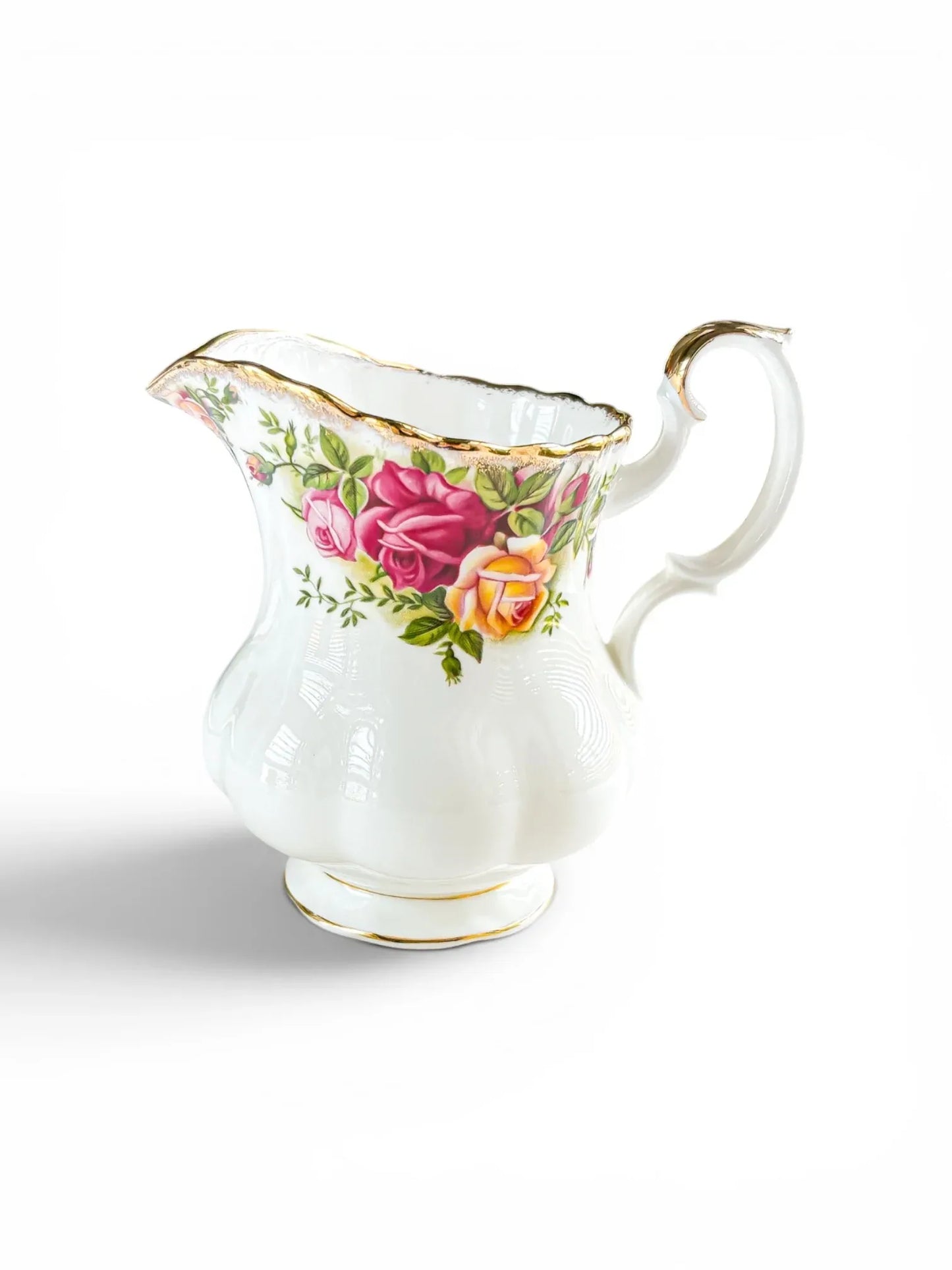 Side profile of a vintage Royal Albert Old Country Roses fine bone china creamer jug against a white background, highlighting the curved Montrose shape, split-twisted handle, and vibrant pink and yellow rose transfers.