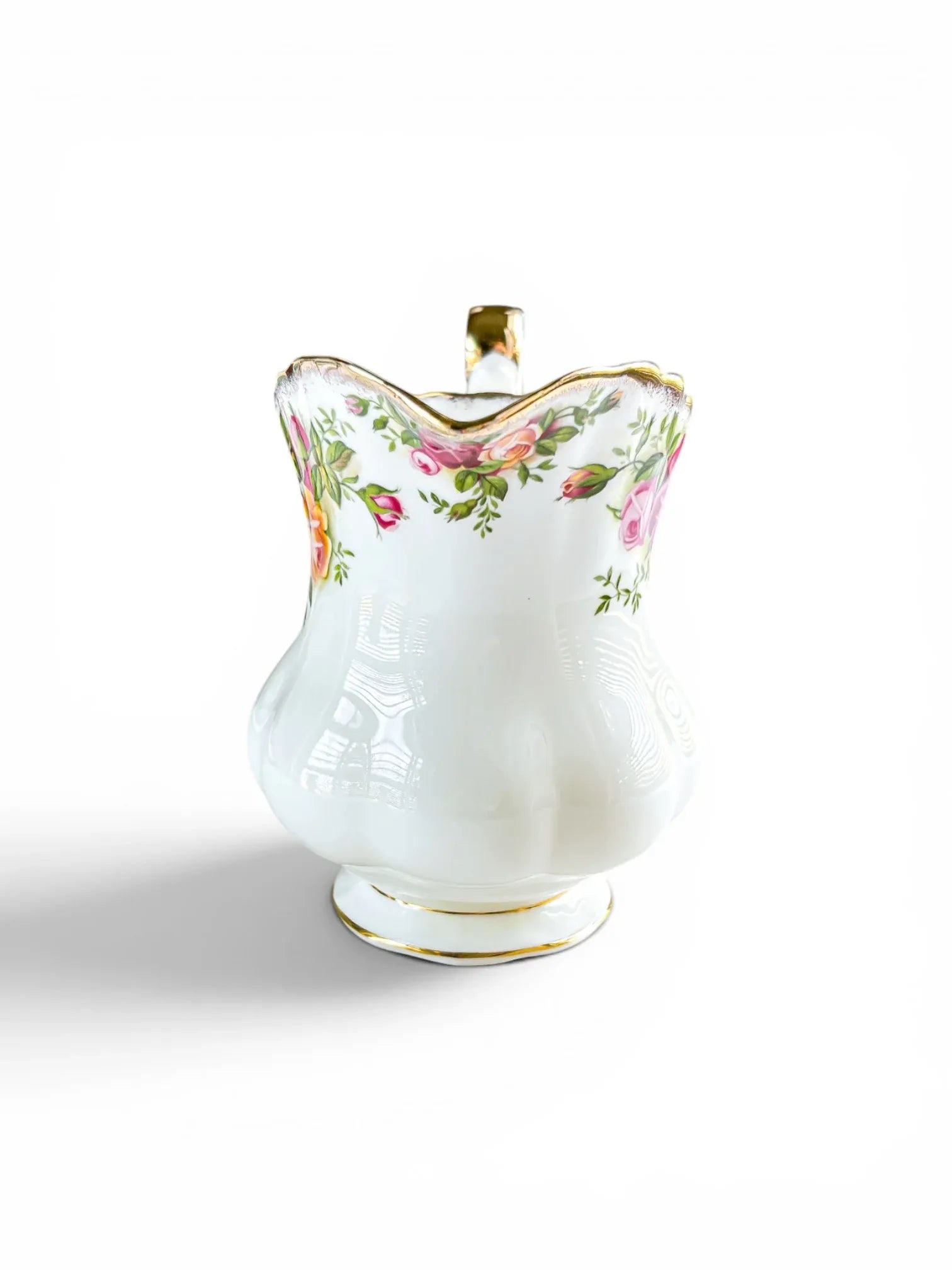Front-facing view of a Royal Albert Old Country Roses creamer jug, showing the delicate floral border along the fluted rim and the smooth, bulbous ceramic base on a white background.