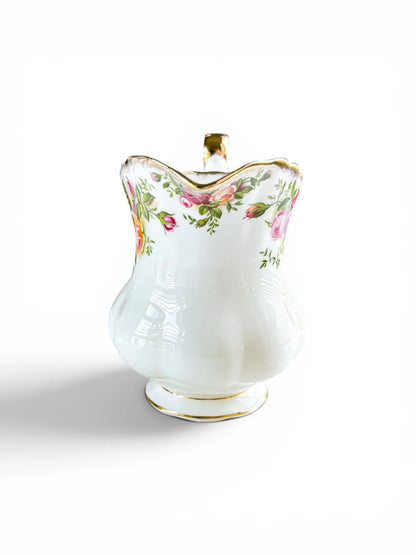 Front-facing view of a Royal Albert Old Country Roses creamer jug, showing the delicate floral border along the fluted rim and the smooth, bulbous ceramic base on a white background.