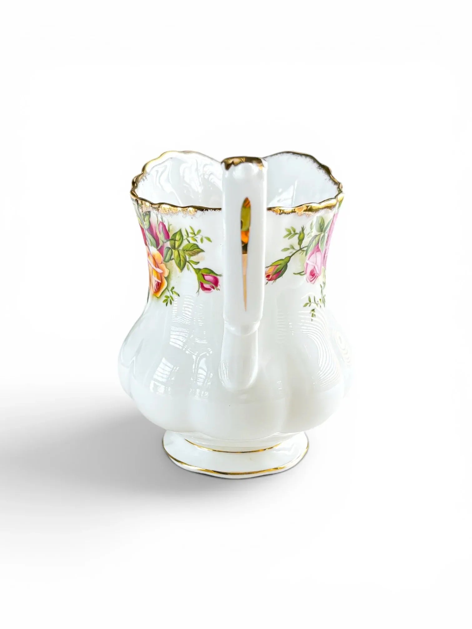 Rear view of the Royal Albert Old Country Roses creamer, centred on the white, porcelain split-twisted handle accented with a hand-applied gold stripe running down the spine.