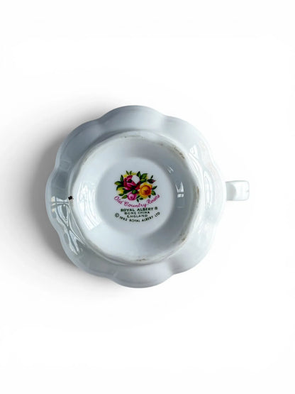 Close-up of the underside backstamp on the scalloped base of the creamer jug, displaying the multi-coloured floral logo and text reading: Royal Albert, Bone China, England, Old Country Roses, Copyright 1962 Royal Albert Ltd.