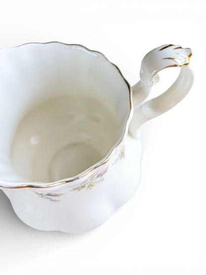 Close-up of the creamer handle showing the elegant scrollwork and minor vintage gold rubbing.