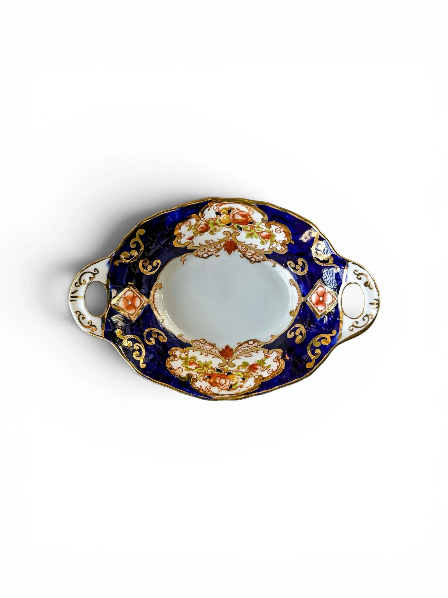 A vintage Royal Albert Derby bone china bonbon dish shown from above. The oval dish features a vibrant cobalt blue border, hand-painted orange floral cartouches, and intricate gold scrollwork against a crisp white background.