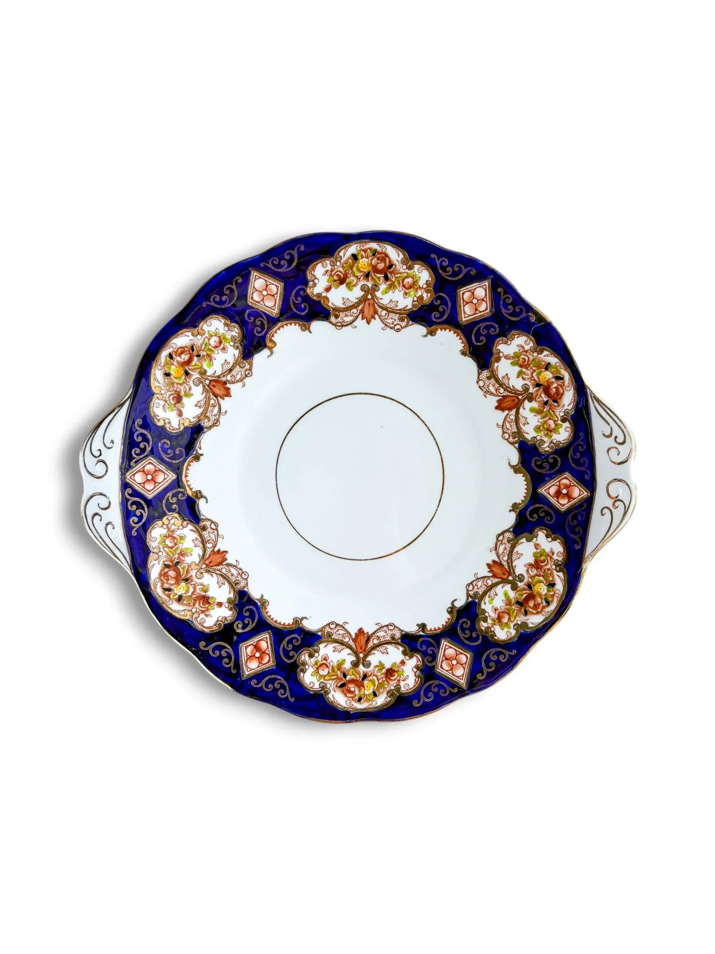 Top-down view of a vintage Royal Albert Heirloom handled cake plate on a clean white background. The design features a deep cobalt blue border with Imari-style burnt orange floral panels and intricate gold filigree.