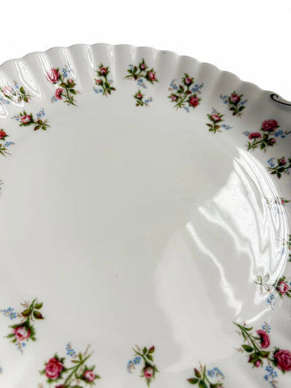 A close-up of the cake plate surface highlighting the light utensil marks and minor gold rubbing on the scalloped rim.