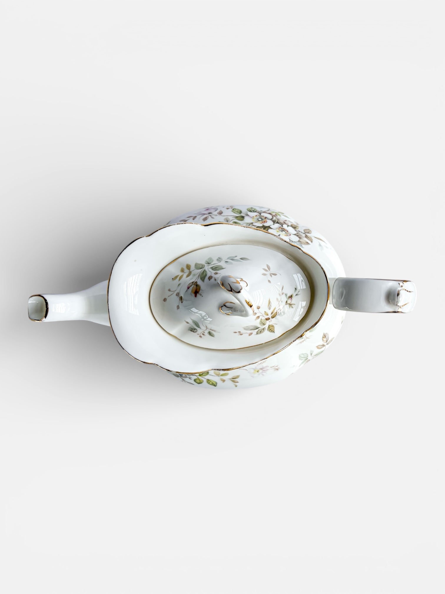 White porcelain teapot with floral and gold trim detail on white background