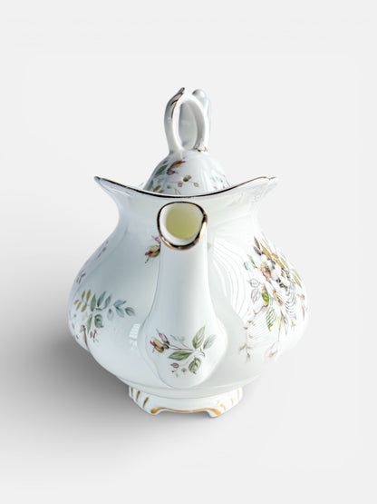 Vintage white porcelain teapot with floral design and gold accents, elegant curved spout and handle