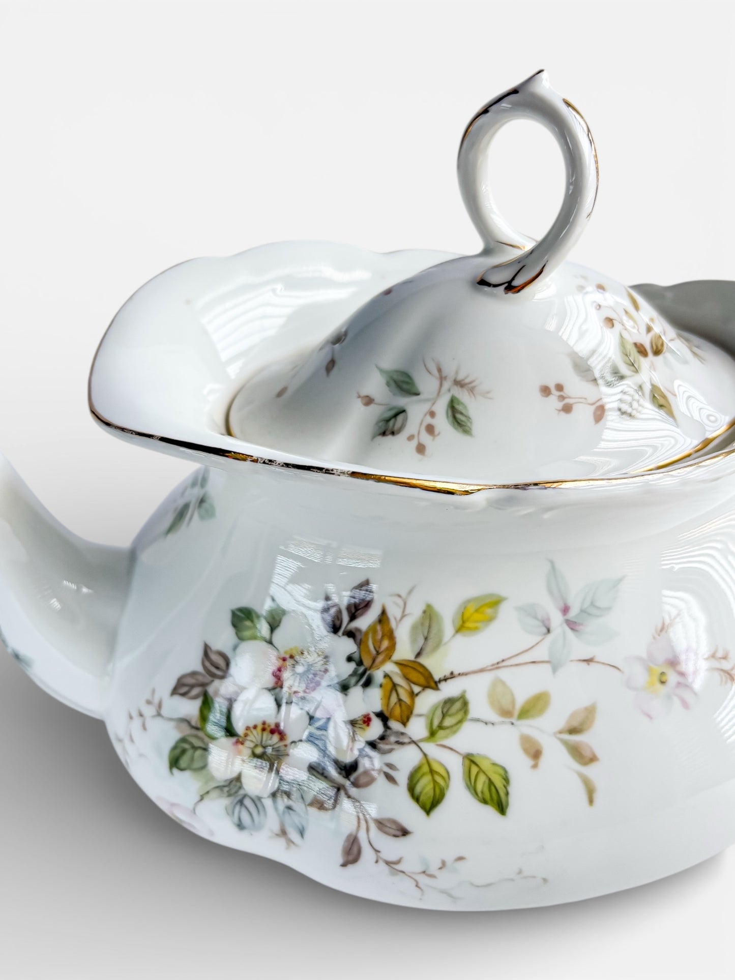 Vintage porcelain teapot with floral pattern and gold trim detail on lid and body