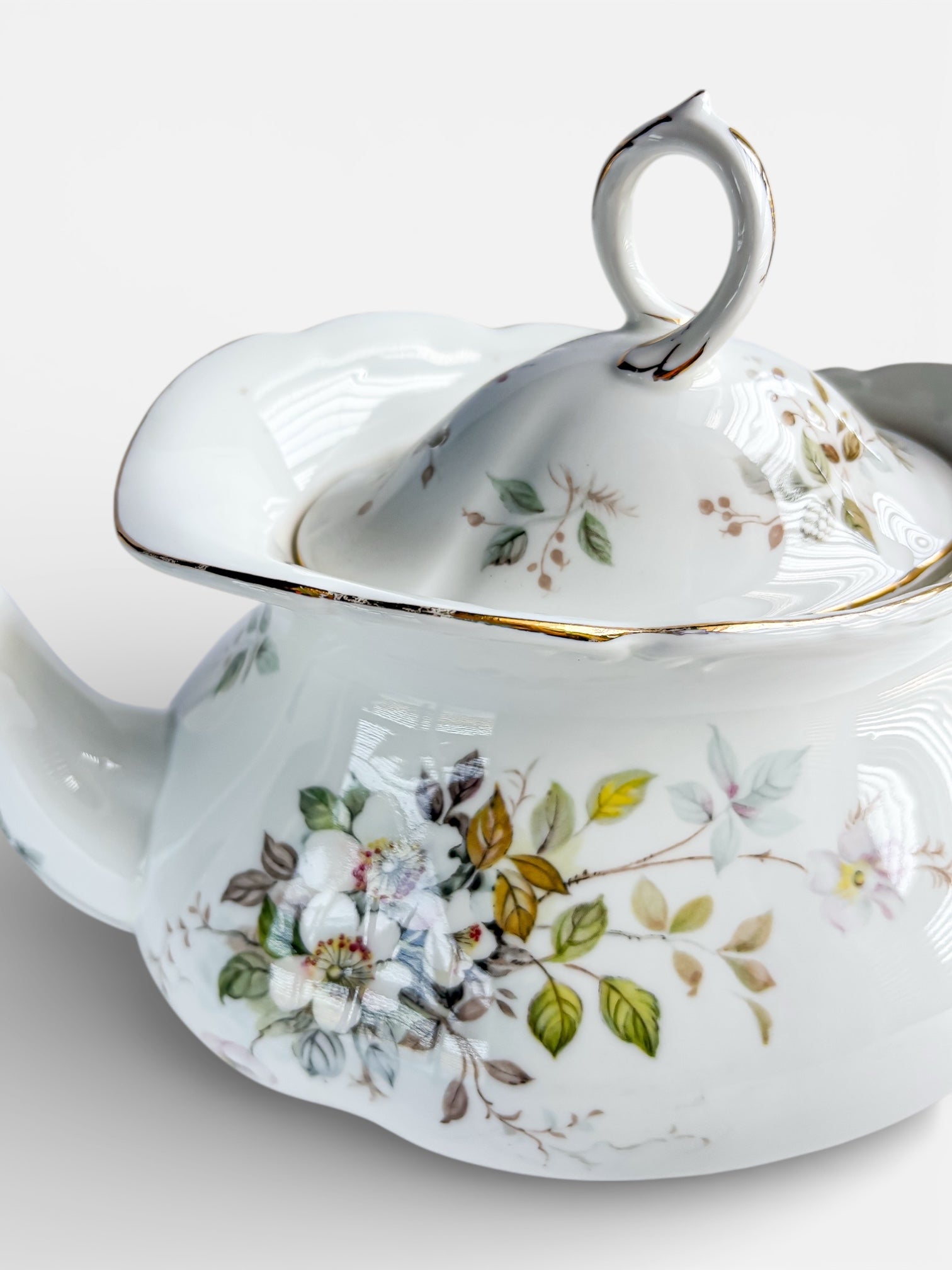 Vintage porcelain teapot with floral pattern and gold trim detail on lid and body