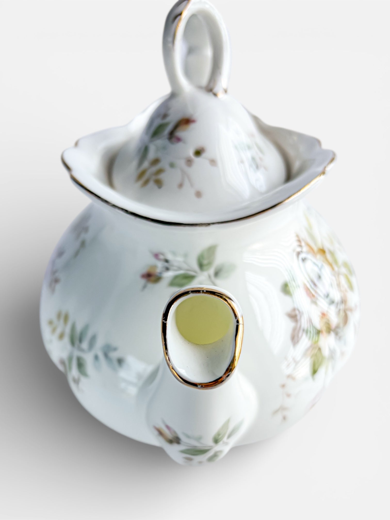 Top view of vintage porcelain teapot with floral patterns and gold-trimmed spout and lid